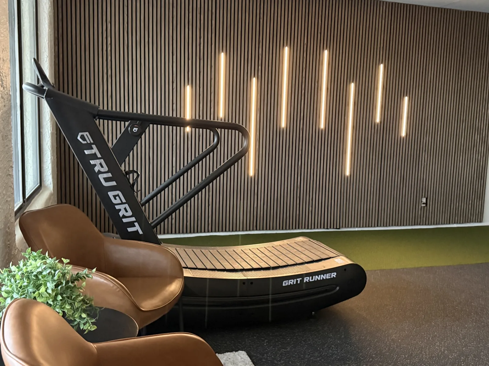 Tru Grit curved manual treadmill beside the slat wall at Solas Physical Therapy in El Paso, used for return-to-running work