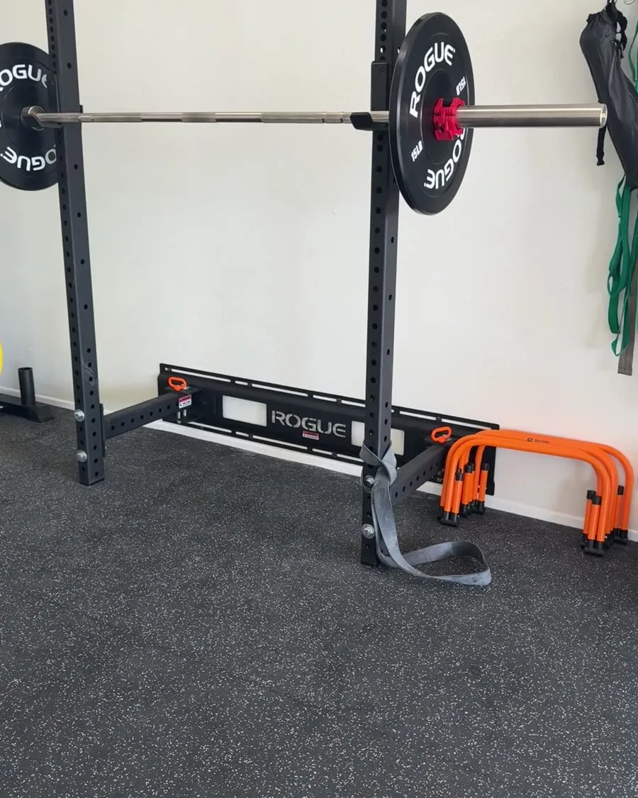 Rogue squat rack loaded with a barbell and bumper plates in the strength training area at Solas Physical Therapy, 300 N Resler Dr, El Paso TX