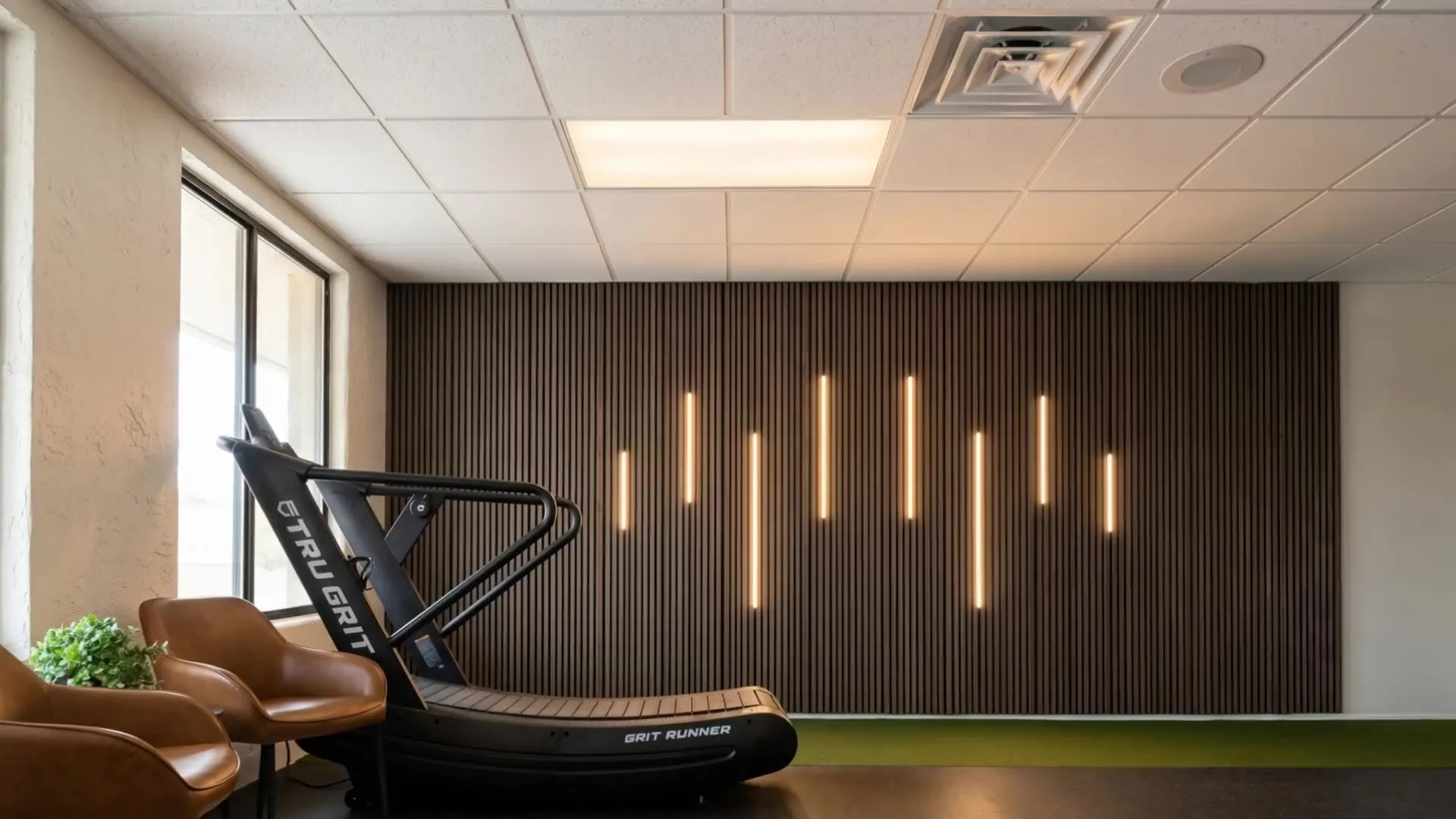 The treatment floor at Solas Physical Therapy, 300 N Resler Dr Ste F, El Paso TX — curved manual treadmill, lit slat wall and turf lane